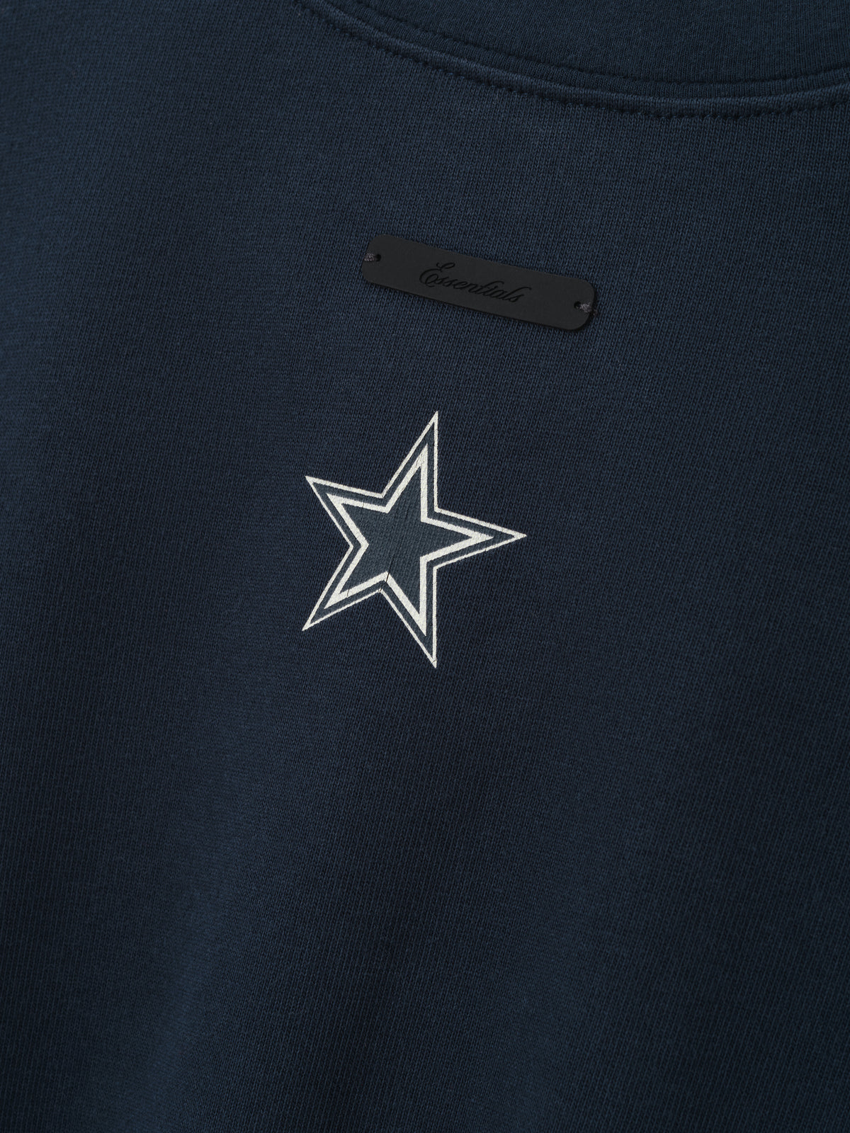 Cowboys Merch Tee navy fabric close up featuring a white outlined star emblem and black chest tag in a detailed Tops product view