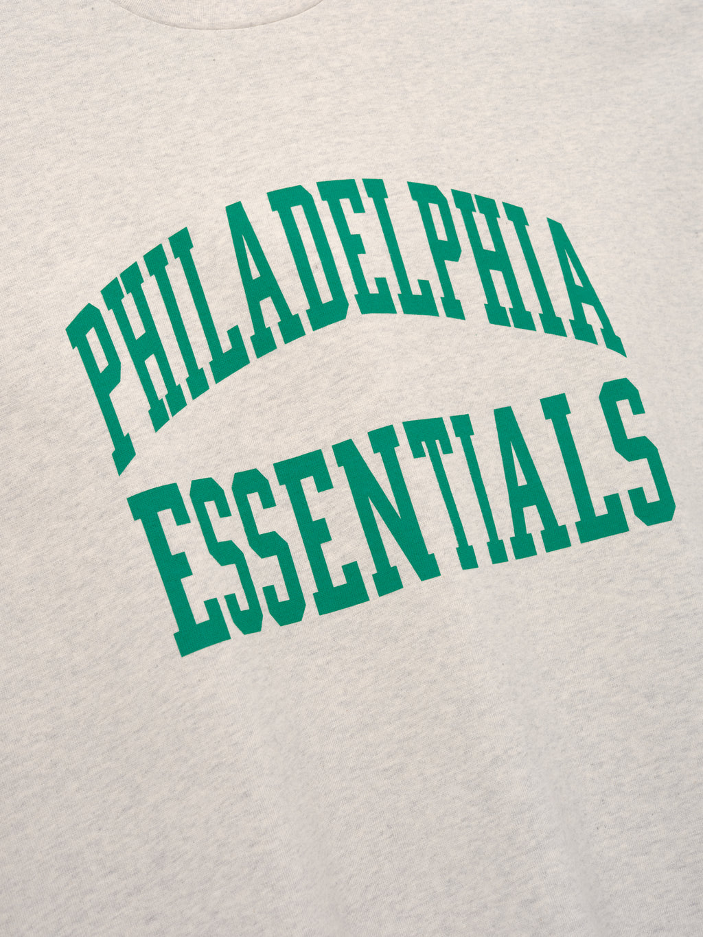 Eagles Merch Tee cream fabric close up with bold green Philadelphia Essentials collegiate lettering in a detailed Tops product view