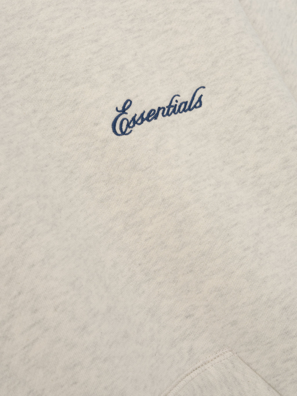 Signature Classic Hoodie in light taupe with blue Essentials script branding on soft textured fabric and a close view of the kangaroo pocket seam as Tops