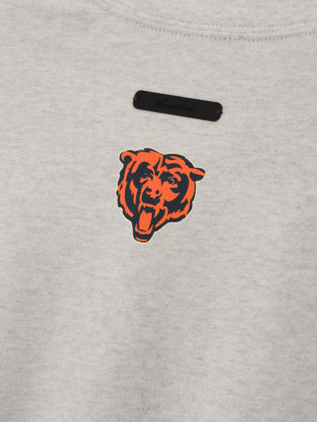 Bears Merch Tee gray fabric close up featuring an orange and black bear head emblem with a black Fear of God label in a detailed Tops product view