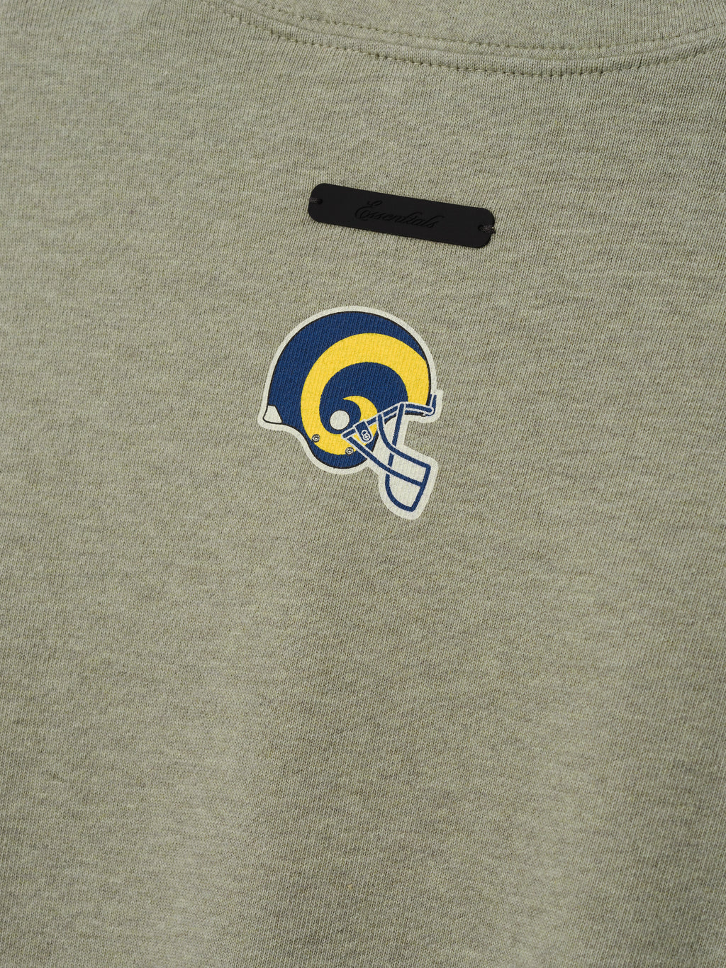 Rams Merch Tee olive gray fabric close up featuring a blue and yellow Rams helmet emblem with black label in a detailed Tops product view