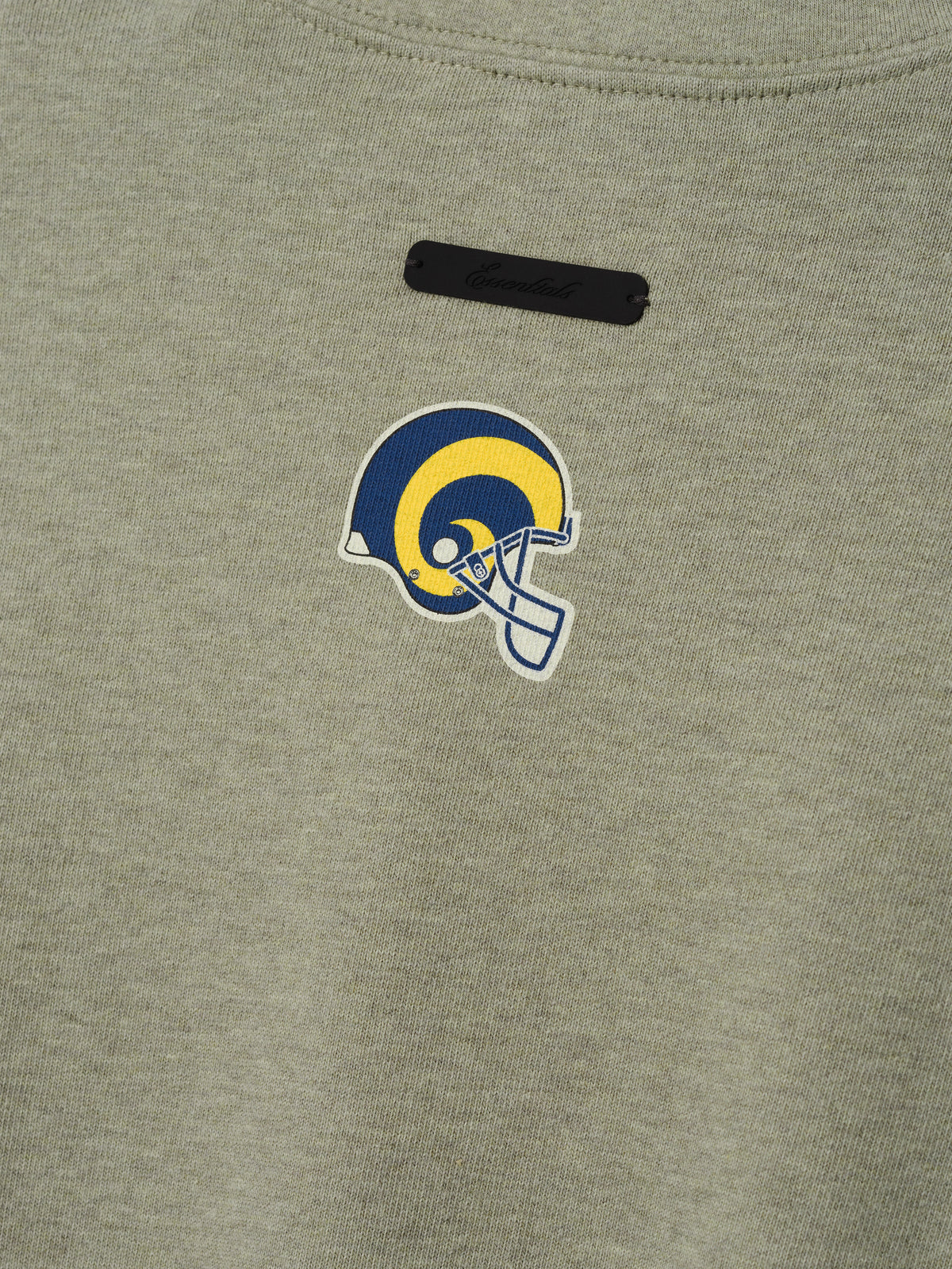 Rams Merch Tee olive gray fabric close up featuring a blue and yellow Rams helmet emblem with black label in a detailed Tops product view