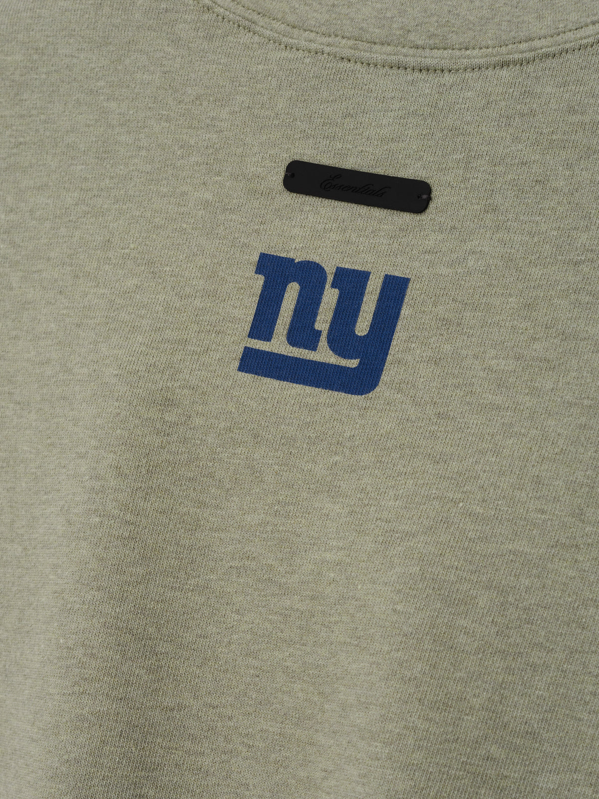 Giants Merch Tee olive gray fabric close up featuring a blue New York Giants logo and black chest label in a clean Tops product detail view