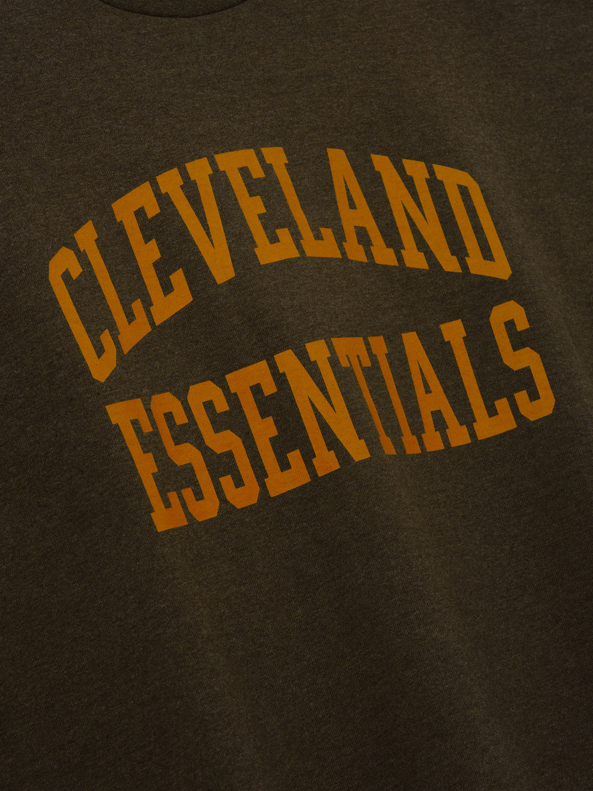 Browns Merch Tee brown fabric close up featuring bold orange Cleveland Essentials collegiate lettering in a detailed Tops product view