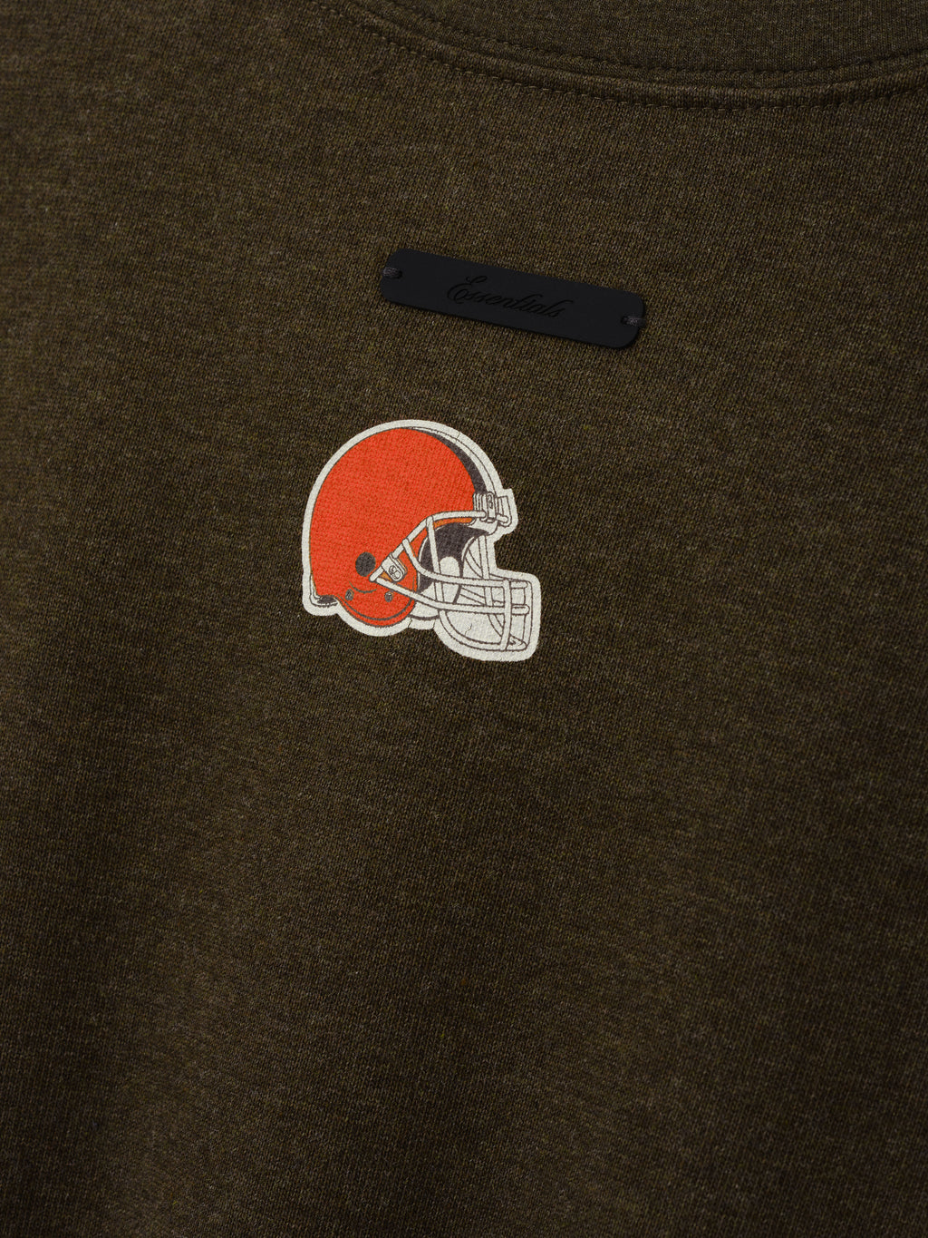 Browns Merch Tee dark brown fabric close up with an embroidered orange Cleveland Browns helmet logo and black chest label in a detailed Tops product view