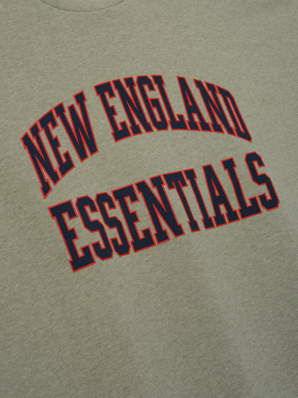 Patriots Merch Tee olive gray fabric close up featuring arched New England Essentials collegiate lettering in red and navy for a clean Tops product detail view