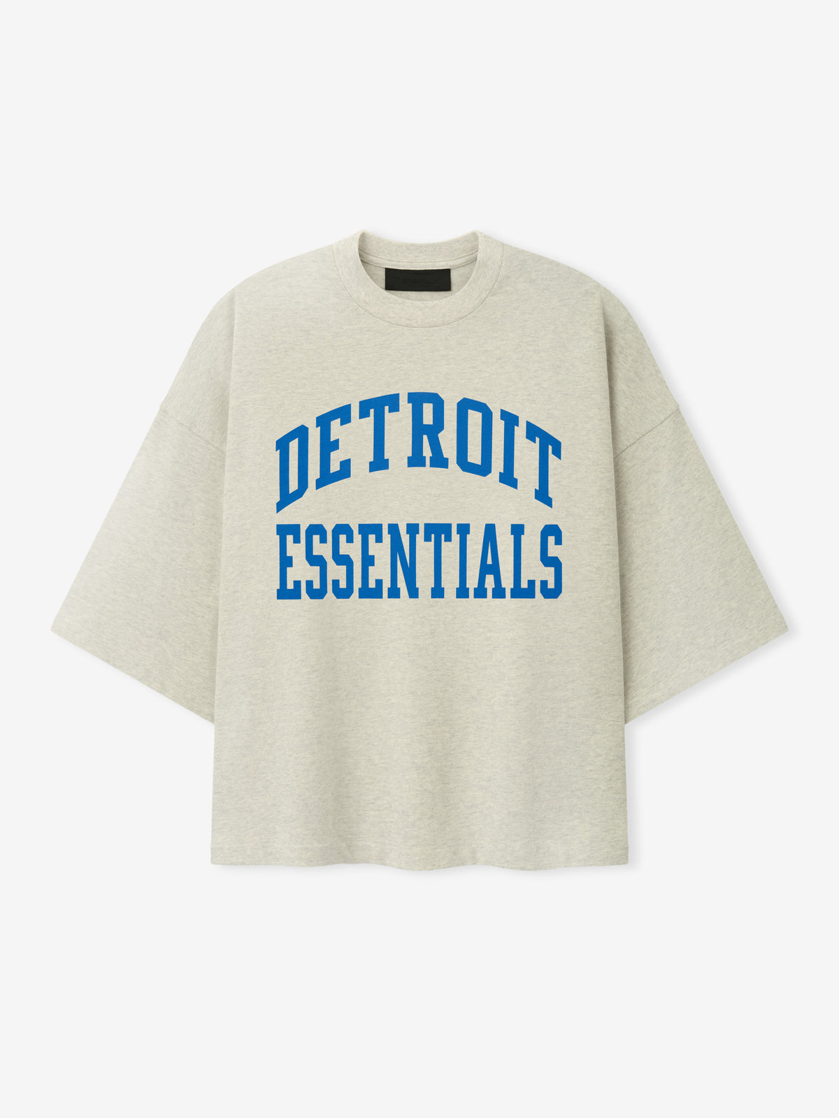 Lions Merch Tee cream oversized short sleeve shirt with bold blue Detroit Essentials collegiate lettering displayed against a light background in a clean Tops product view