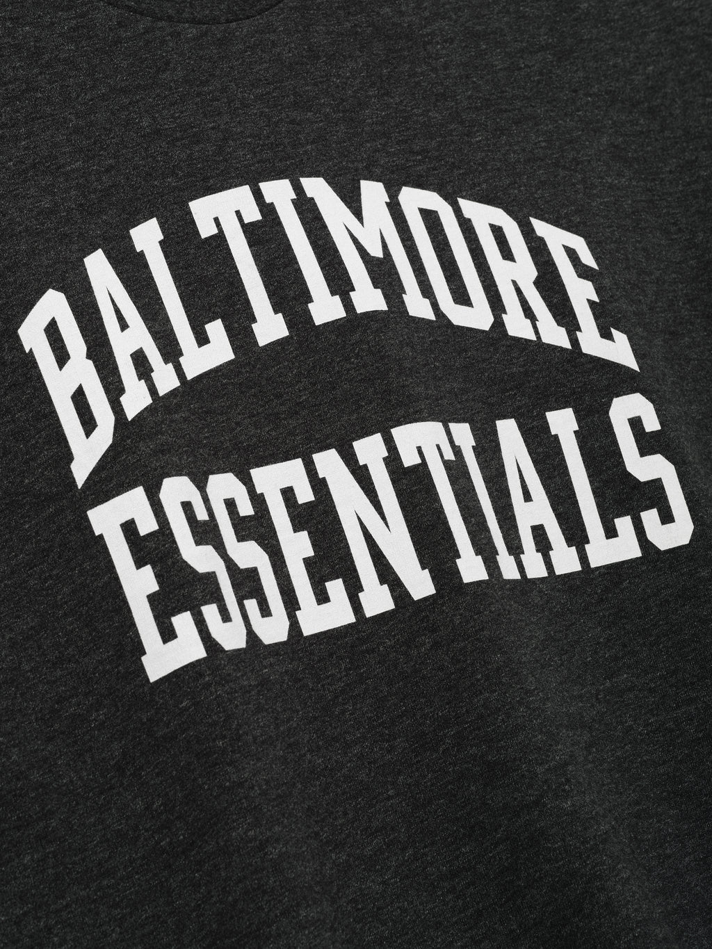 Ravens Merch Tee dark charcoal fabric close up with bold white Baltimore Essentials collegiate lettering in a detailed Tops product view