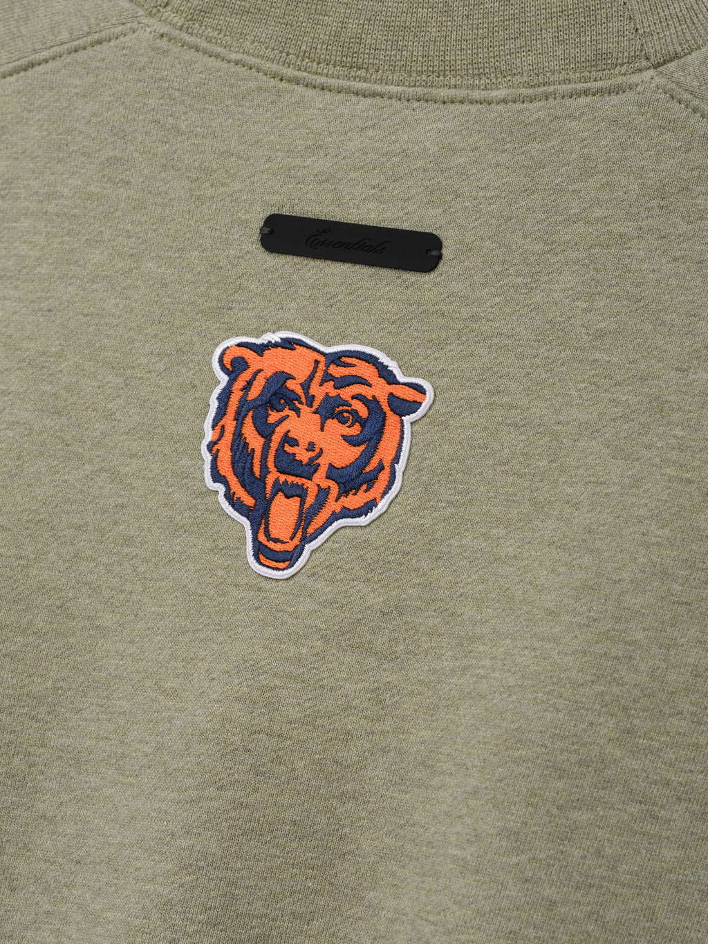 Bears 90s Relaxed Crewneck olive green sweatshirt close up with embroidered Chicago Bears head logo and black chest label shown in a detailed Tops product view