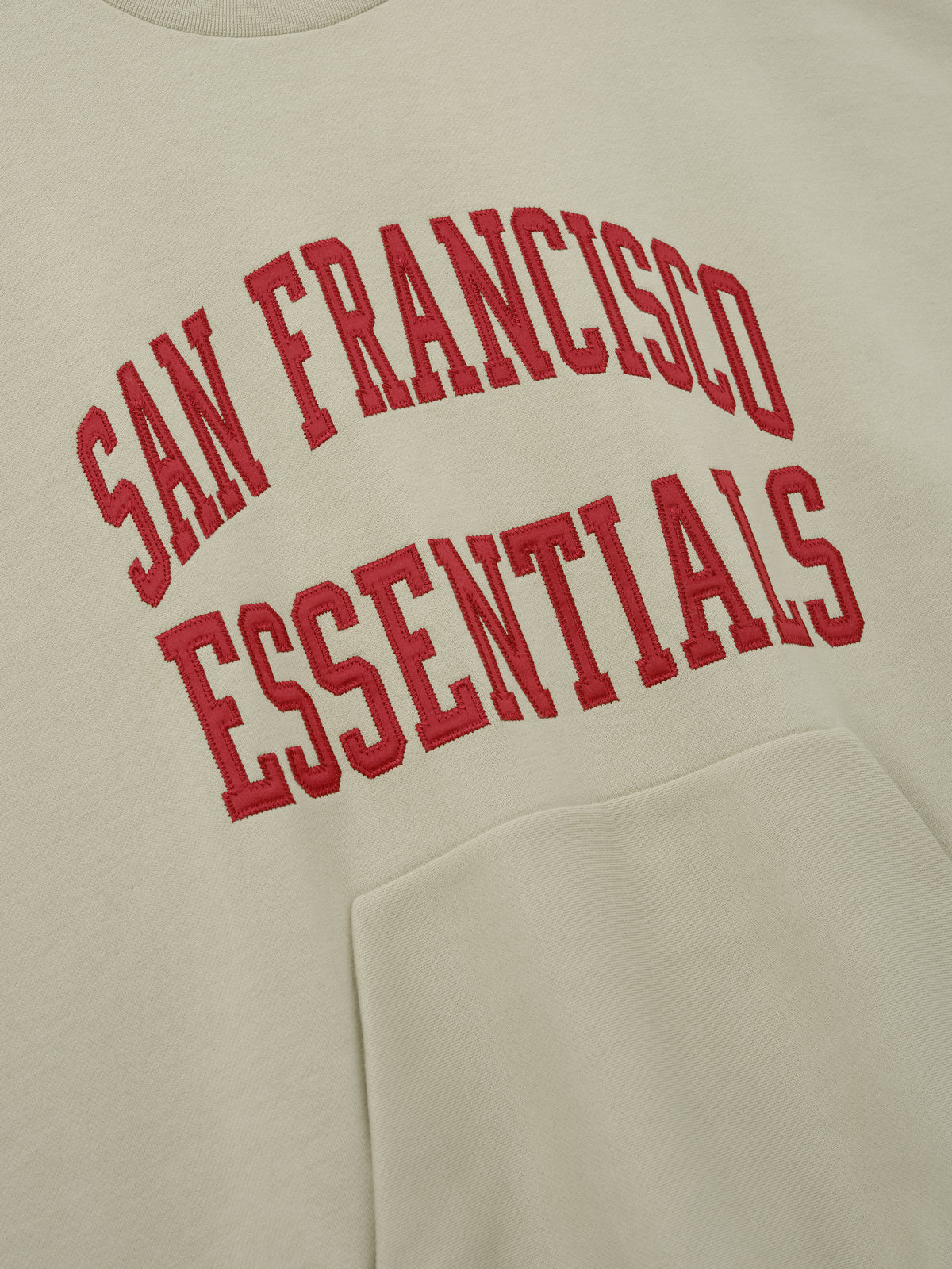 49ers 90s Relaxed Crewneck cream sweatshirt with red San Francisco Essentials collegiate lettering and kangaroo pocket shown in a clean Tops product view