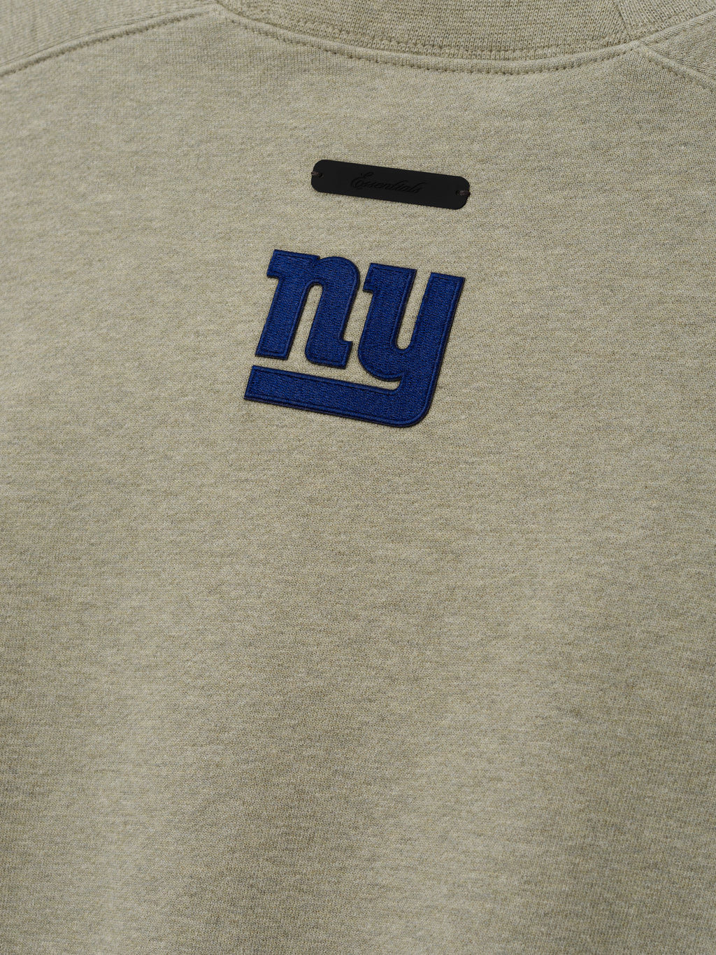 Giants 90s Relaxed Crewneck stone sweatshirt close up featuring an embroidered blue New York Giants logo and black chest label shown as a Tops product detail