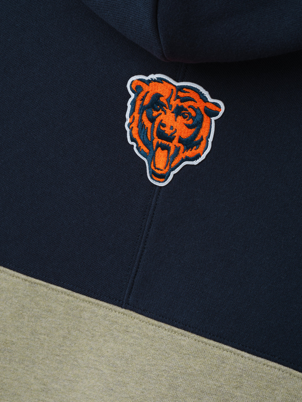 Bears 90s Relaxed Hoodie close up showing an embroidered orange bear head logo on navy fabric above khaki color blocking as a Tops product detail