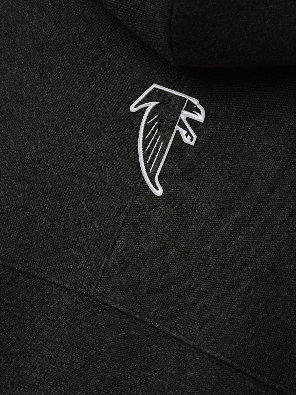 Falcons 90s Relaxed Hoodie close up in black with an embroidered white Atlanta Falcons logo on soft fleece fabric as a Tops product detail