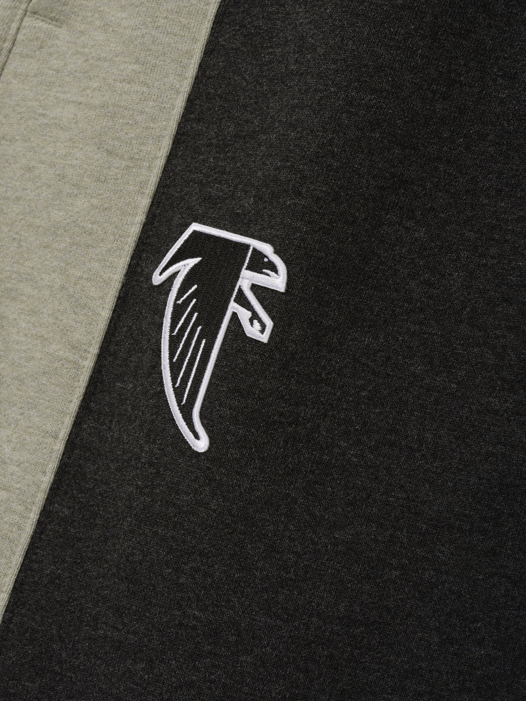Falcons Lounge Sweatpant close up in black fleece with gray side panel and white embroidered falcon emblem shown as a Bottoms product detail