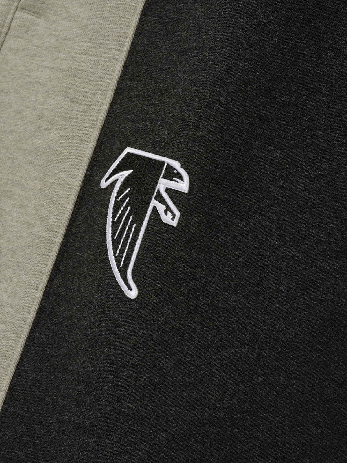 Falcons Lounge Sweatpant close up in black fleece with gray side panel and white embroidered falcon emblem shown as a Bottoms product detail