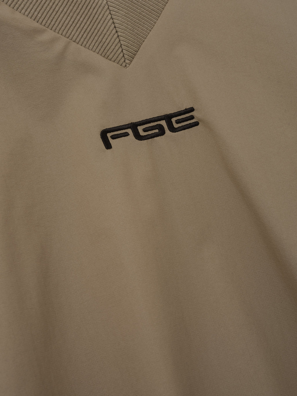Womens Pullover Track Jacket in taupe with a black Fear of God FOG chest logo and ribbed V neck collar shown in close detail as Outerwear