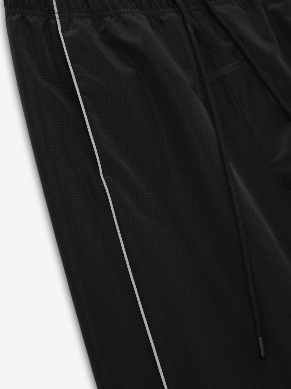 Ripstop Classic Track Pant in black with white side piping and a zippered pocket detail shown in close up against a light background as Bottoms