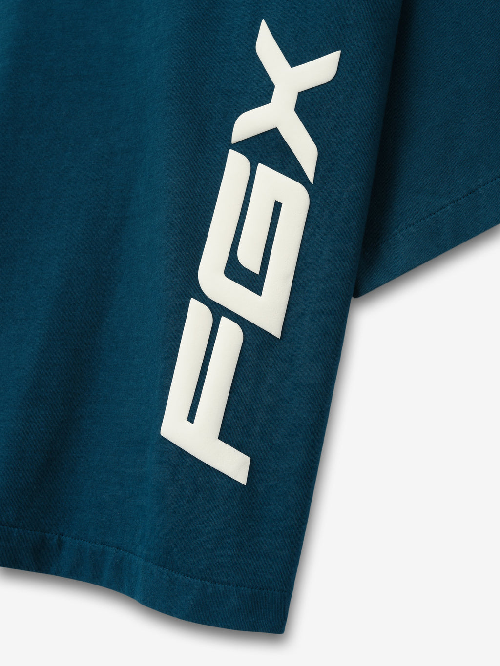 Merch Tee in dark teal with bold white vertical PXG graphics on the short sleeve shown in close up as Tops