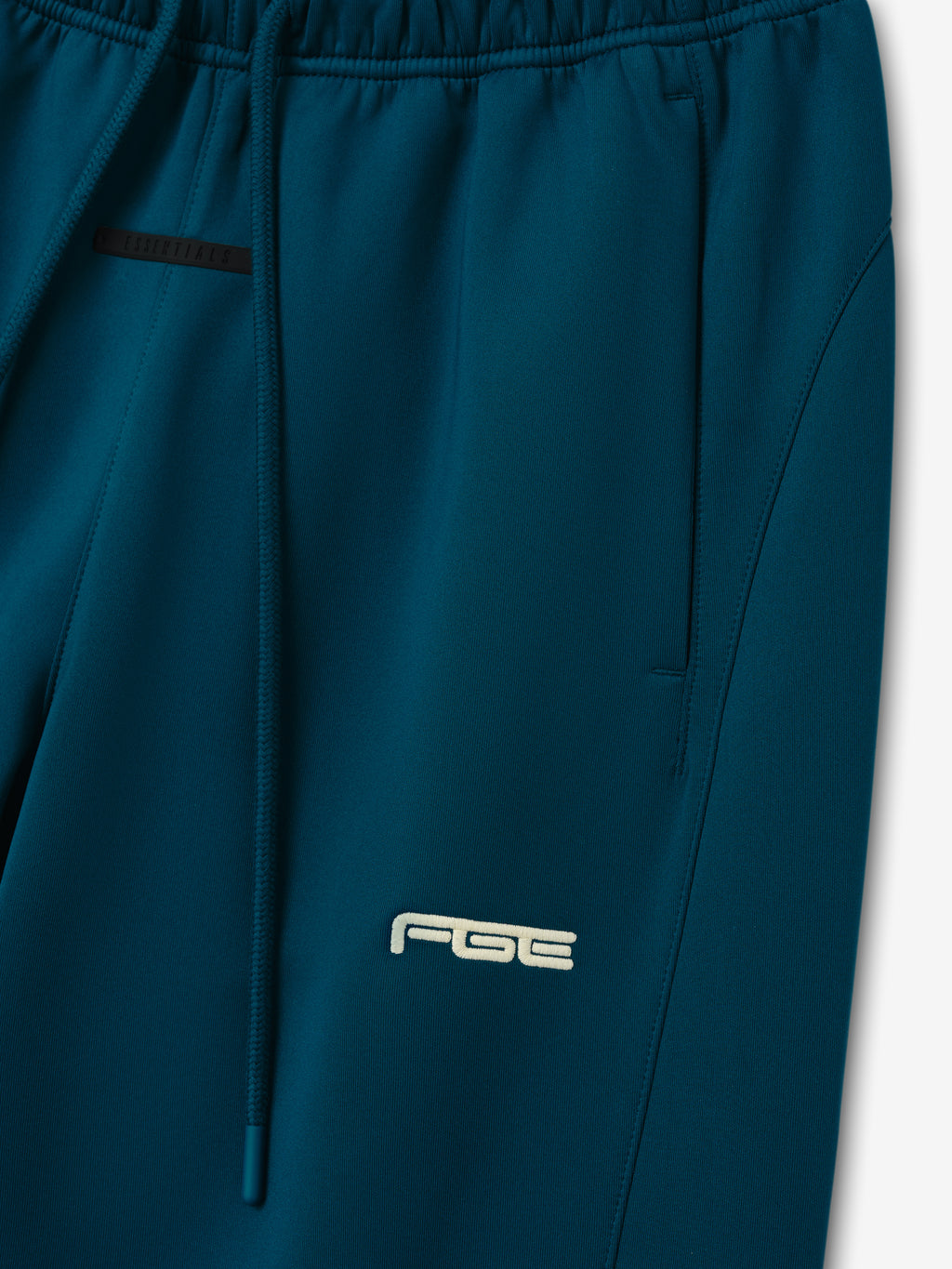 Womens Slim Trackpant in deep teal with an elastic waistband drawstring side pocket and subtle logo shown in close detail as Bottoms