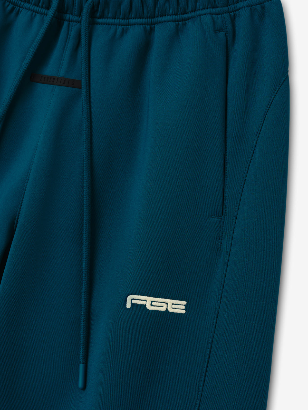 Womens Slim Trackpant in deep teal with an elastic waistband drawstring side pocket and subtle logo shown in close detail as Bottoms
