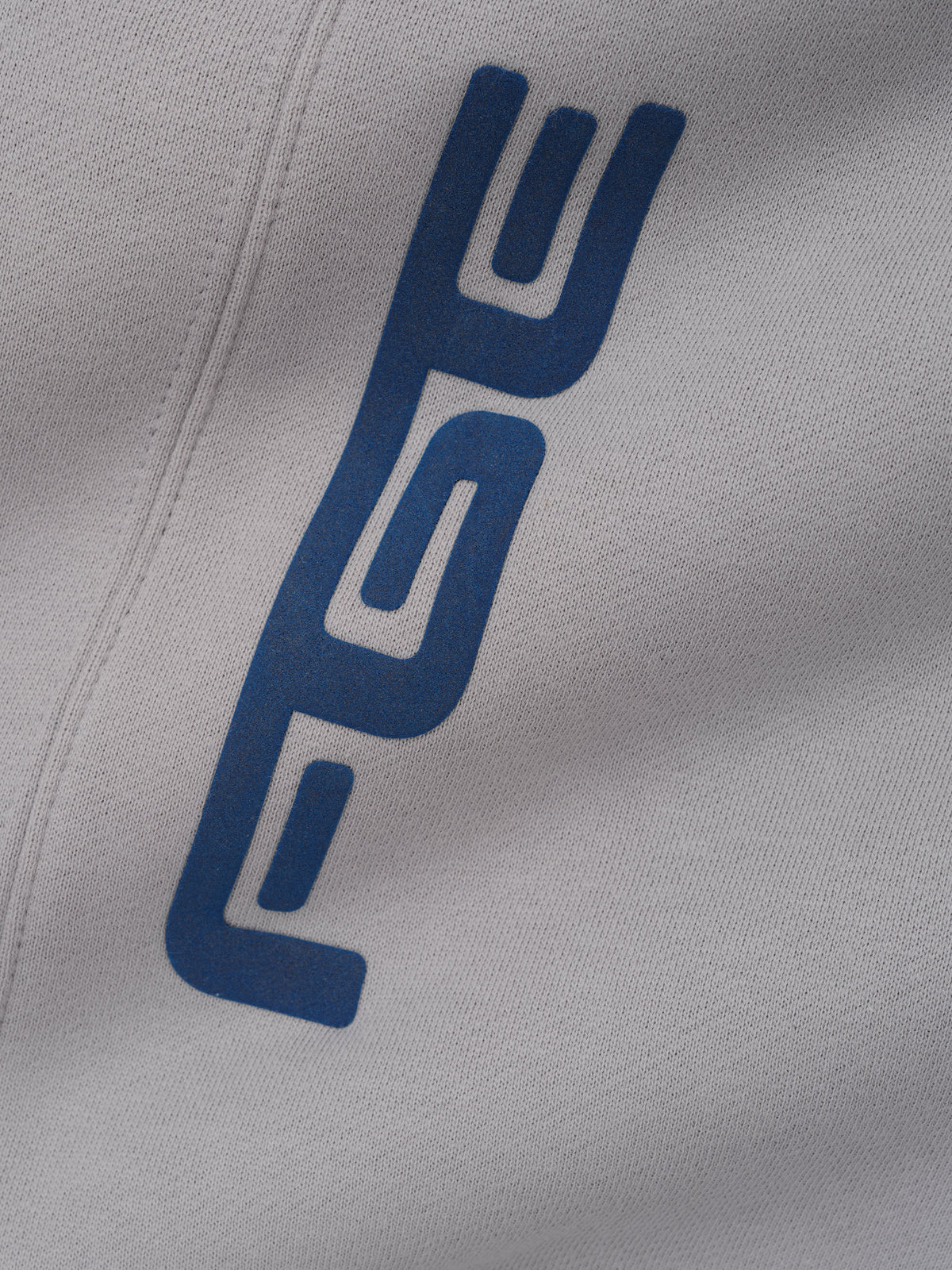 Kids Classic Moto Sweatpant in gray shown in close detail with a vertical blue logo and stitched seam on soft fabric as Bottoms