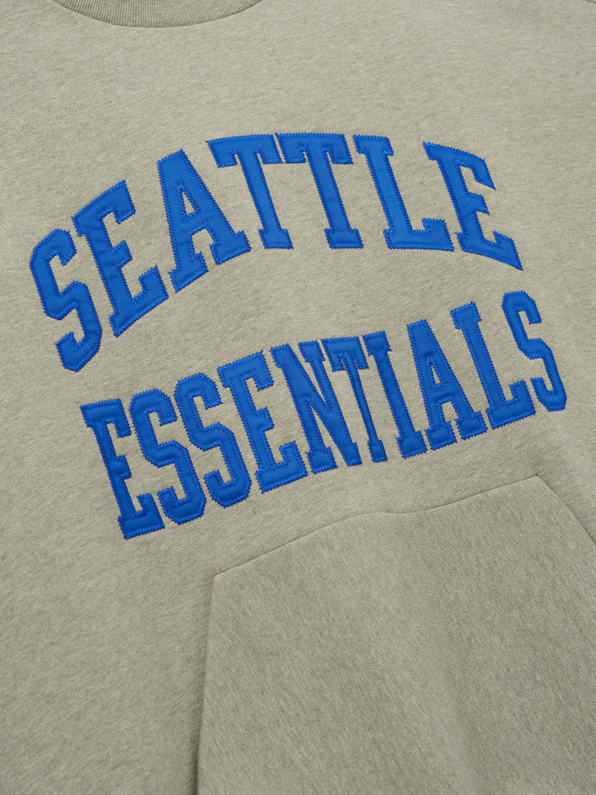 Seahawks 90s Relaxed Crewneck in sage green fleece with bold blue Seattle Essentials lettering and kangaroo pocket shown as a Tops product detail