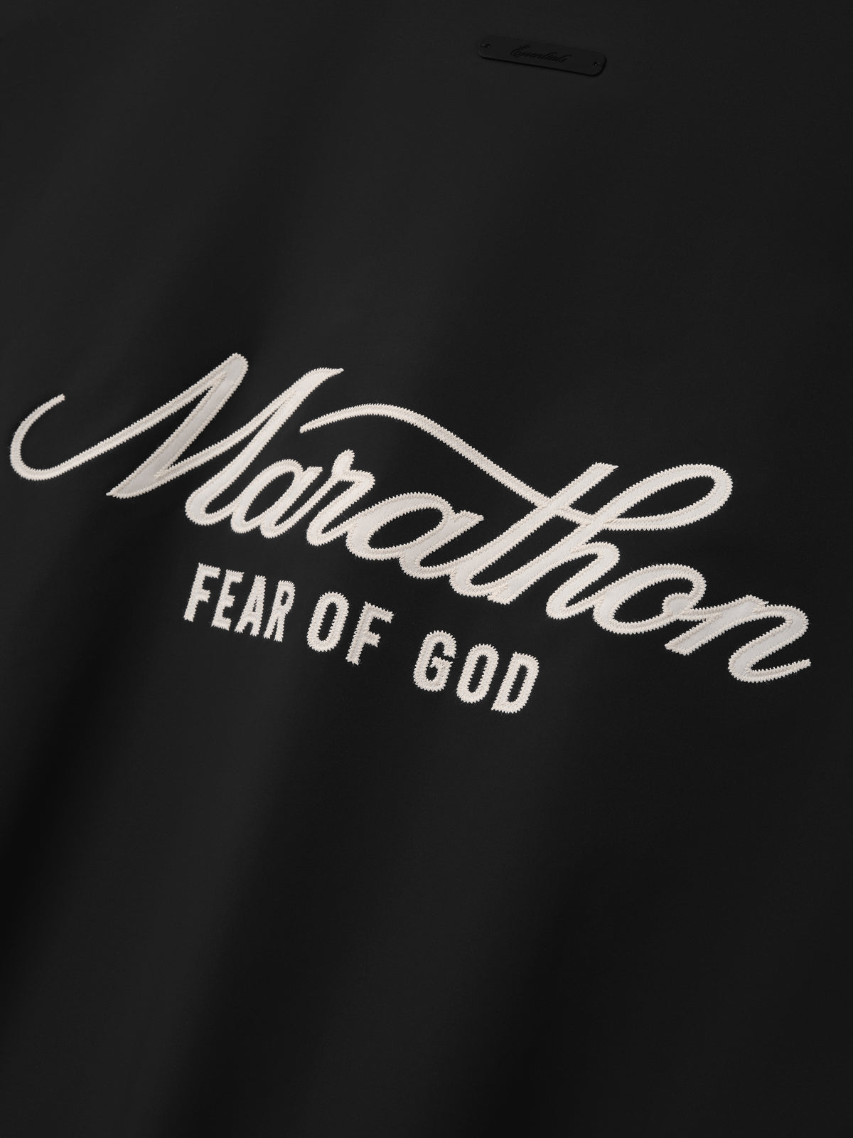 Marathon Modern Track Jacket in black featuring a close up of the white Marathon script and Fear of God logo detail as Outerwear