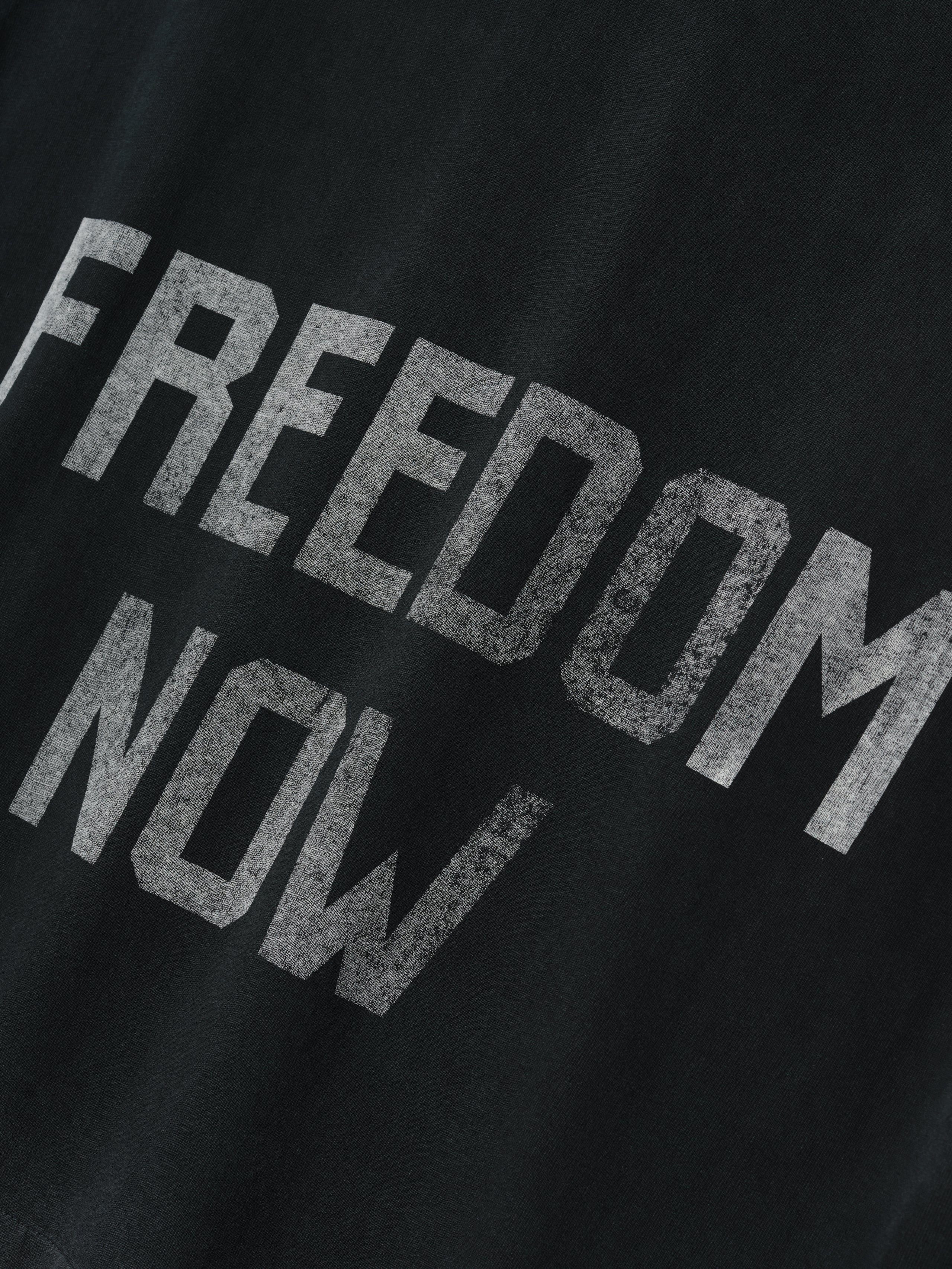 Freedom Relaxed Long Sleeve Tee in black with distressed white “FREEDOM NOW” lettering printed on soft cotton fabric, offering a relaxed fit for casual tops styling.