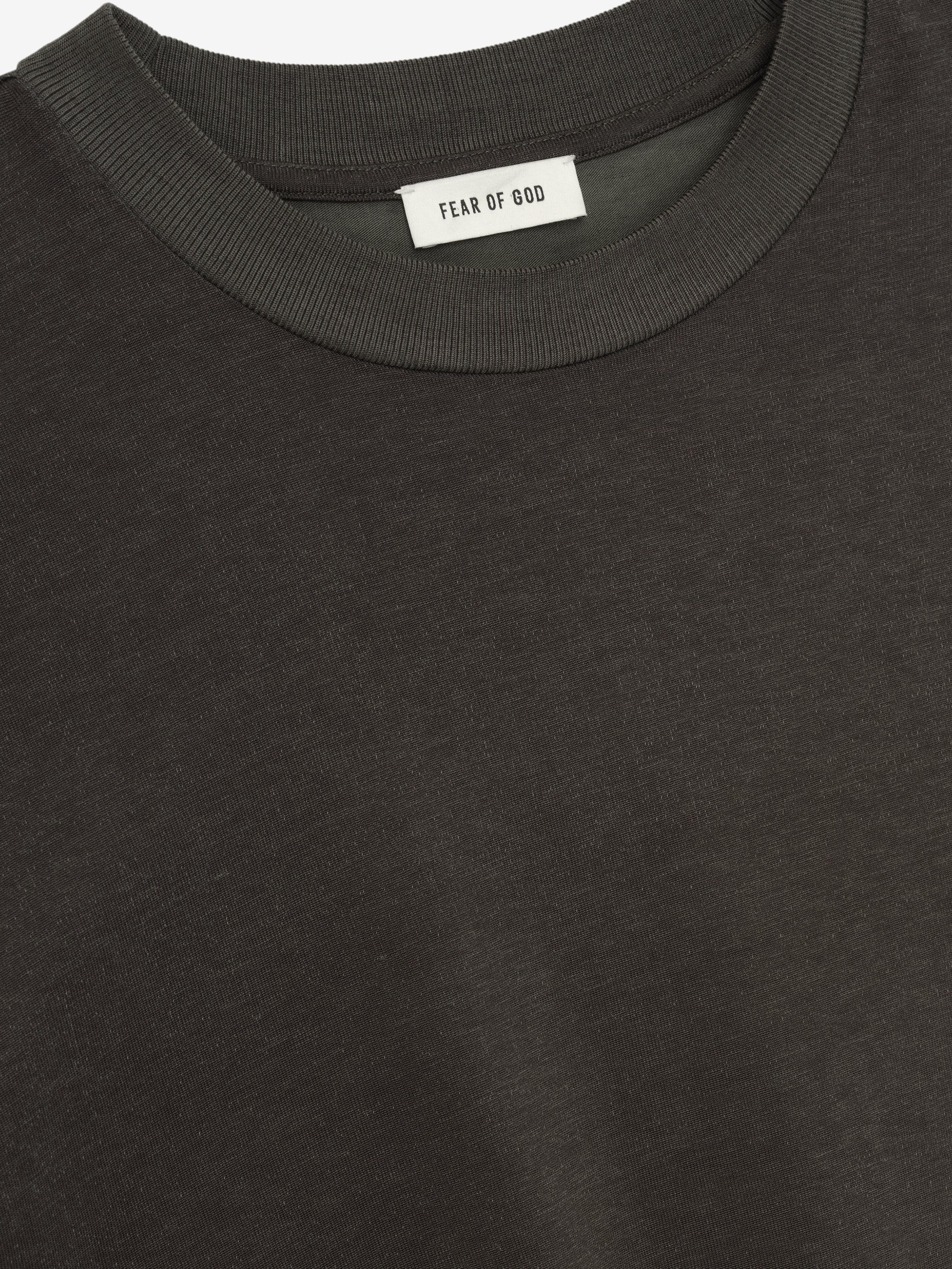 Close-up view of an off-black Cotton Viscose Relaxed Tee showing fine fabric texture and a ribbed crew neckline with an inner label against a plain background.