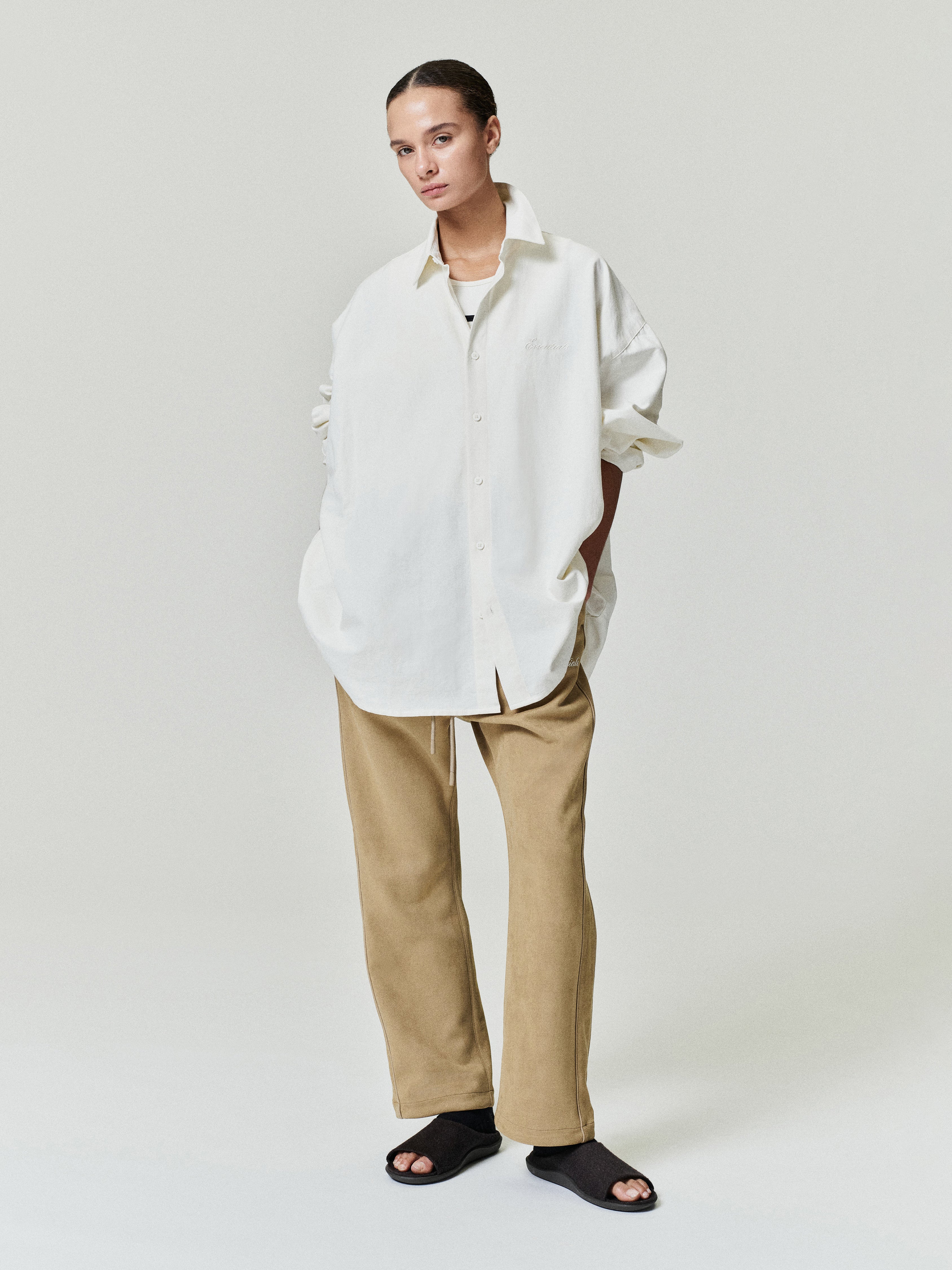 woman wearing oversized white brushed cotton oxford shirt with long sleeves and beige straight-leg pants