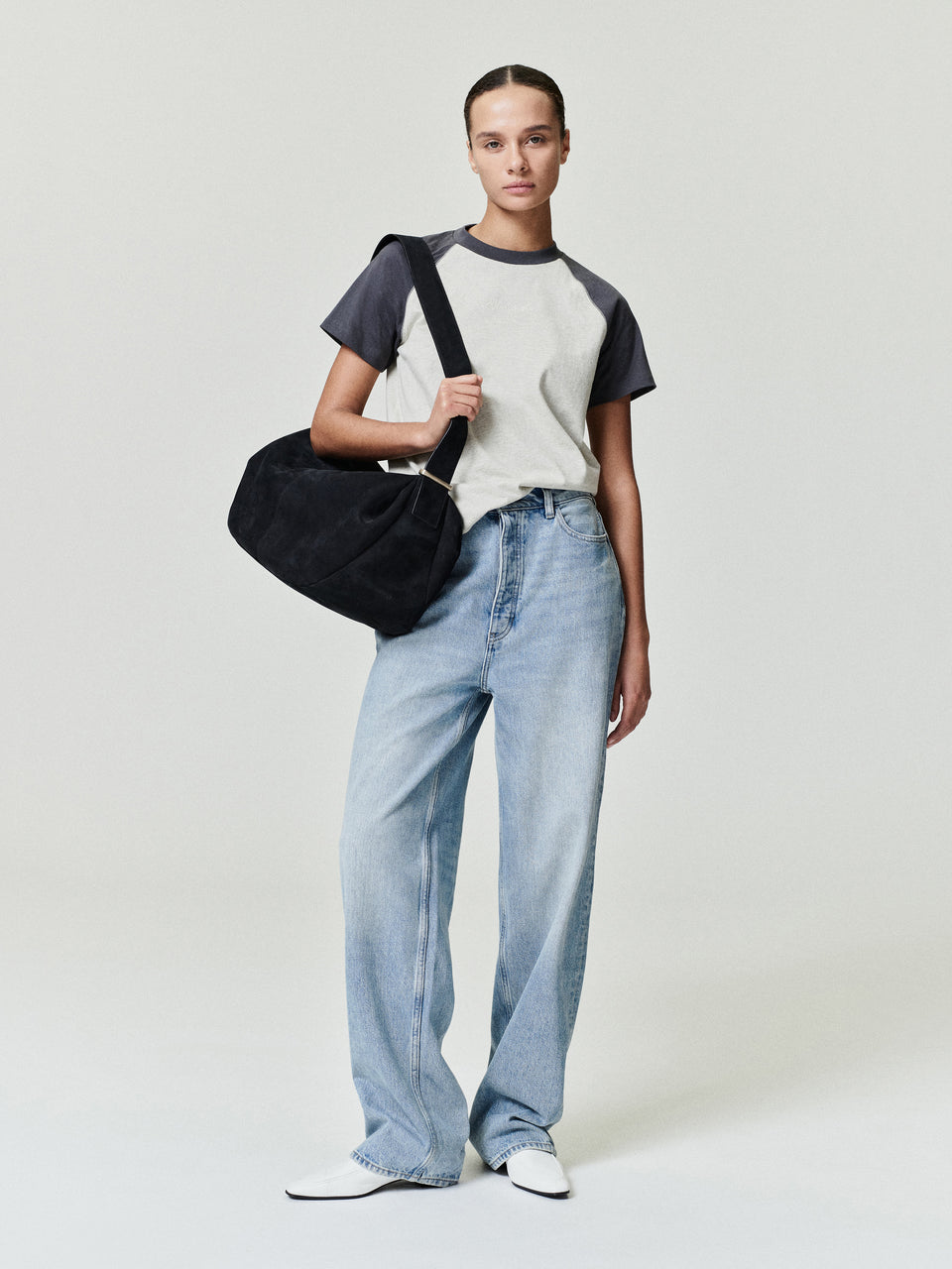 Person wearing a gray sweater and light blue jeans on a plain background