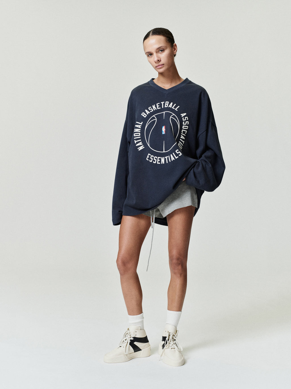 oversized navy cotton long sleeve V-neck tee with circular NBA Essentials basketball graphic center chest