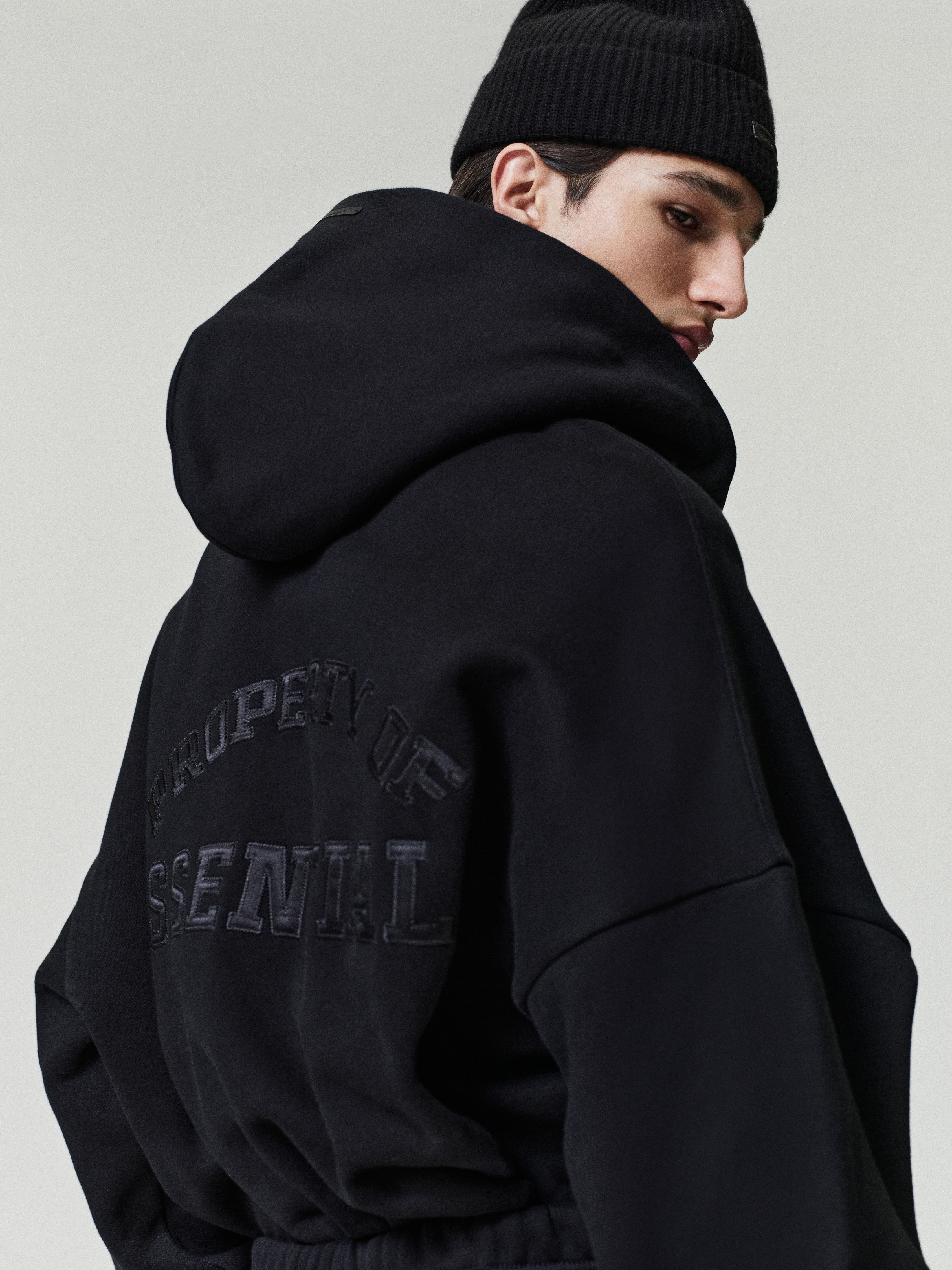 angled rear view of black heavyweight fleece half-zip hoodie with satin stitch Essentials Property logo on back