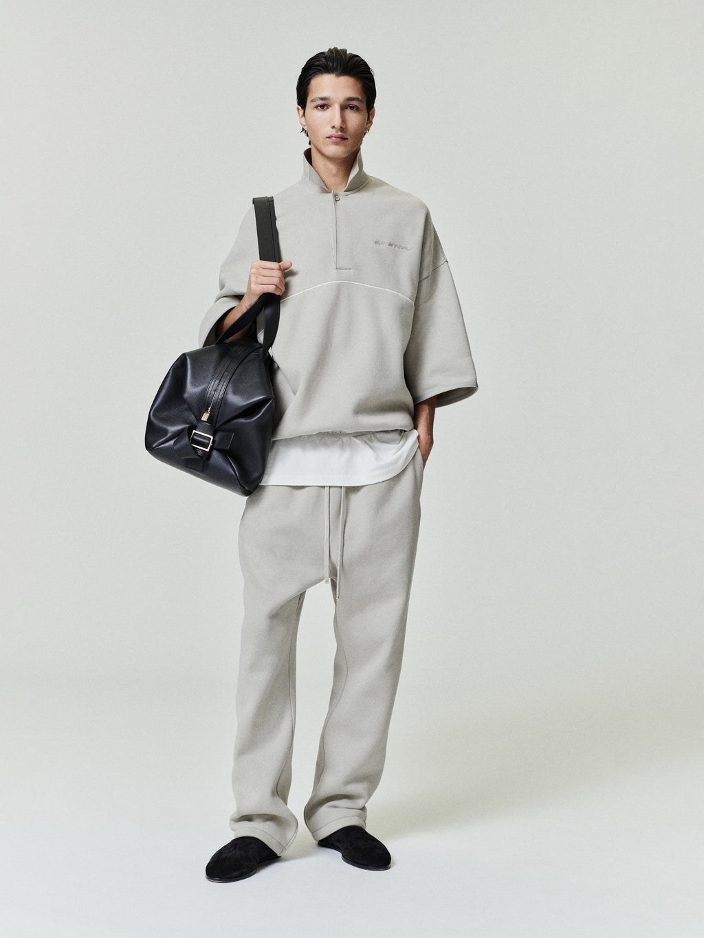 model wearing light beige relaxed fit sweatpants with drawstring waist and matching oversized quarter-zip pullover