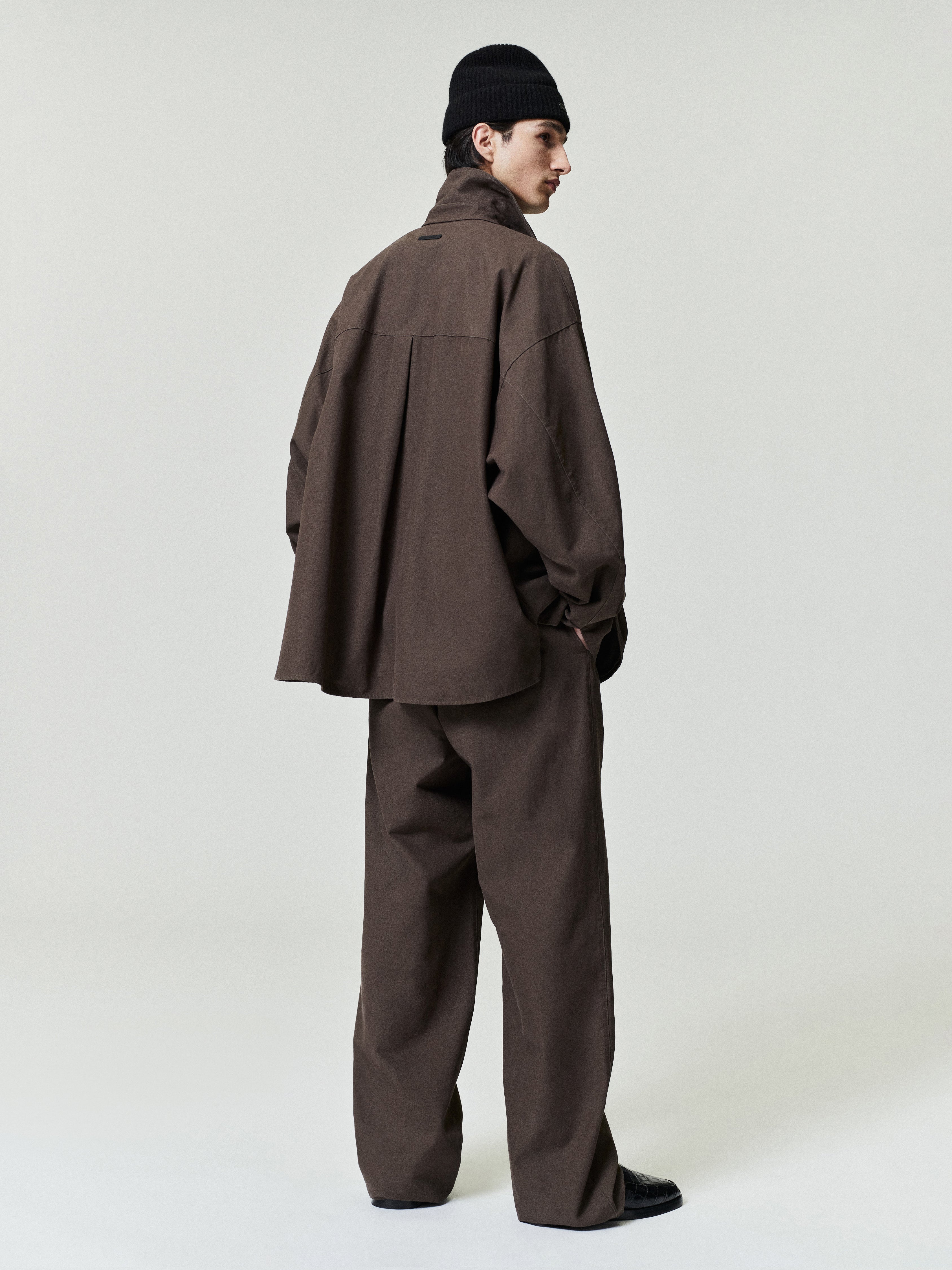Person wearing a brown outfit with a matching beanie on a white background