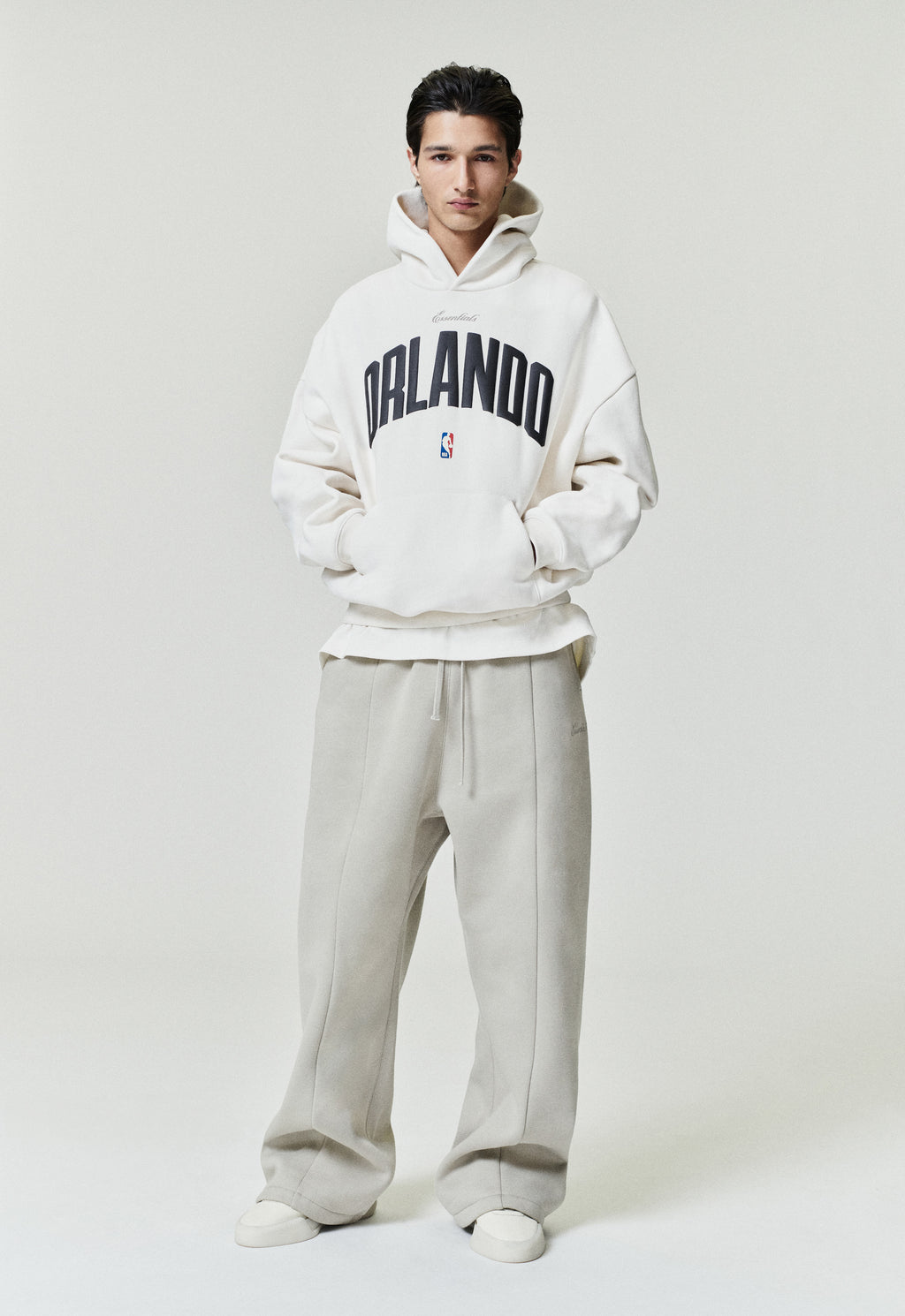 Front view of model wearing off-white Orlando Magic 90s Hoodie with black Orlando text and small NBA logo, image SP26_F_L64-P_3090