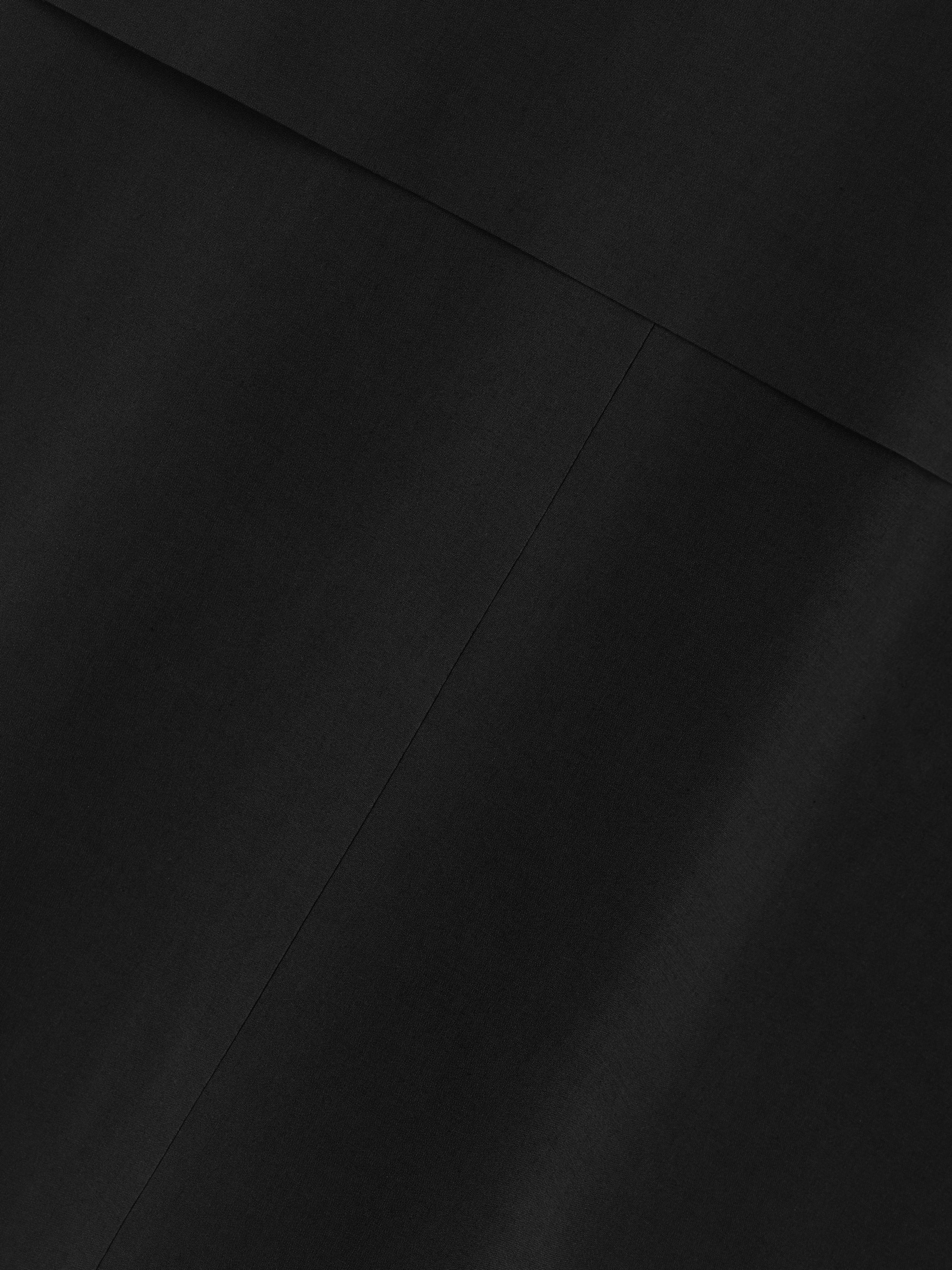 close-up view of smooth black stretch wool blend fabric with subtle seam detail on technical trench jacket