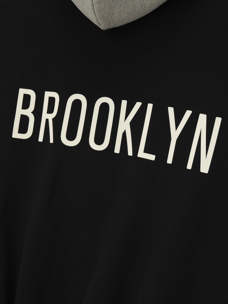 Close-up of black hoodie with contrasting grey hood and large white BROOKLYN text across the back panel