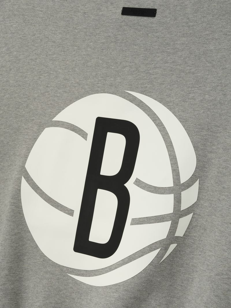 Close-up of grey crewneck with large white basketball graphic and bold black letter B on front center