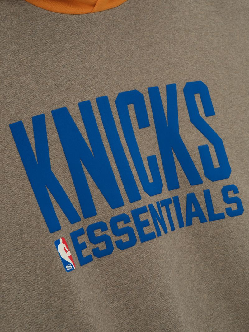 Close-up of brown Knicks Sport Hoodie with bold blue KNICKS ESSENTIALS lettering and partial view of orange hood w_fxRX3A.jpg